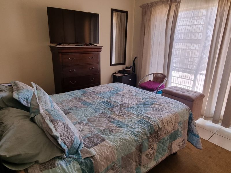 A functional bedroom featuring tiled flooring and a sliding glass door that provides access to an outdoor area, allowing for natural light.