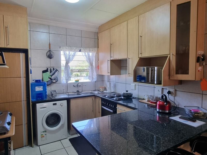 A functional kitchen featuring light wood cabinetry, granite countertops, tiled backsplash, and integrated appliances, offering a practical layout for daily use.
