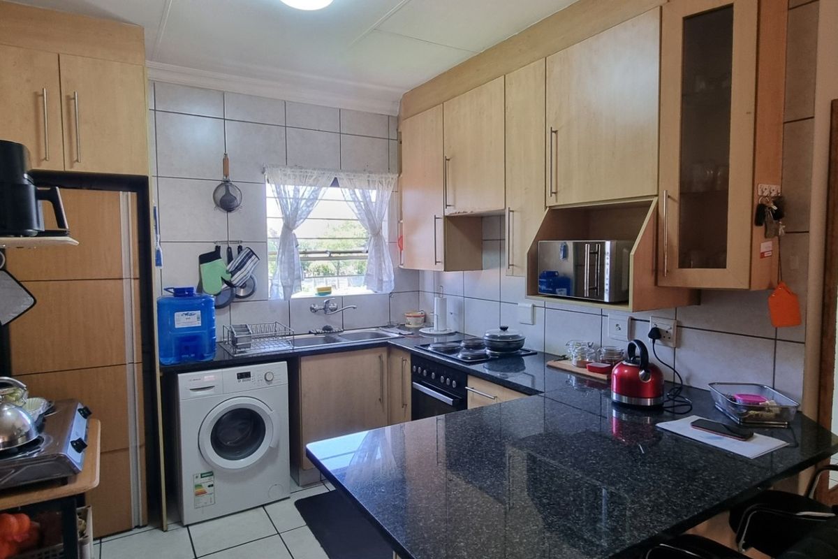 A functional kitchen featuring light wood cabinetry, granite countertops, tiled backsplash, and integrated appliances, offering a practical layout for daily use.
