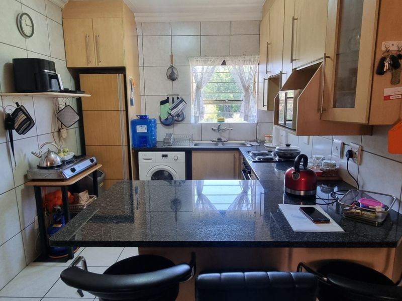 Functional kitchen featuring granite countertops, ample built-in cabinetry, tiled backsplash, and integrated cooking appliances, offering a practical layout for daily meal preparation.