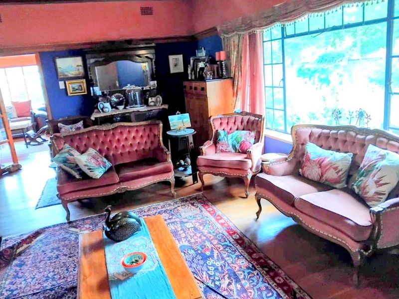 A traditional living room featuring hardwood flooring, a large multi-pane window, and classic architectural details like picture rails and coved ceilings.
