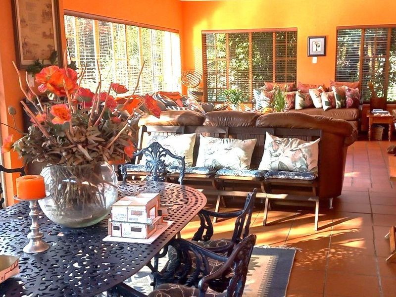 Spacious open-plan living and dining area featuring terracotta floor tiles and large windows with venetian blinds, offering a bright and connected living space.