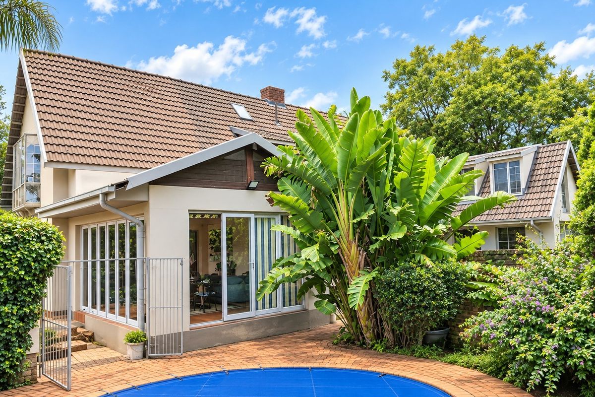 Rear view of the house featuring a brick-paved patio area, a swimming pool with a cover, and large sliding glass doors leading indoors.