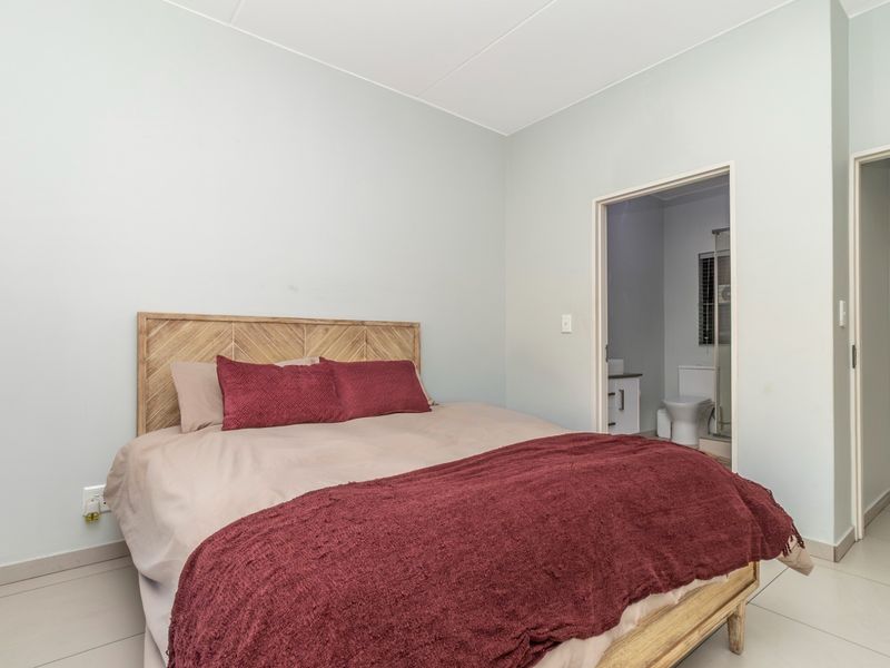 A well-maintained bedroom featuring neutral tiled flooring and direct access to an en-suite bathroom.