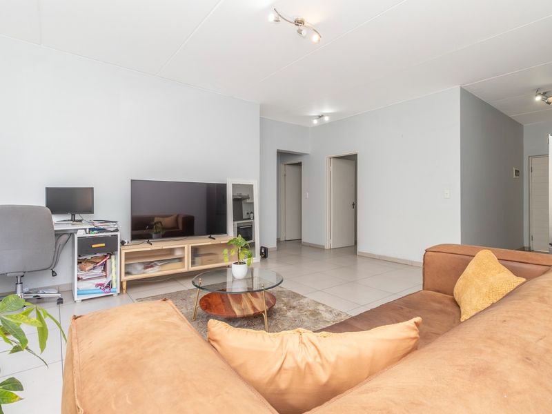 A spacious living room featuring neutral tiled flooring and multiple internal access points, providing a versatile layout for comfortable daily living.
