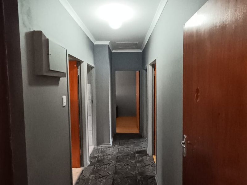 A functional hallway featuring tiled flooring, neutral wall finishes, and access to multiple rooms via internal doors.