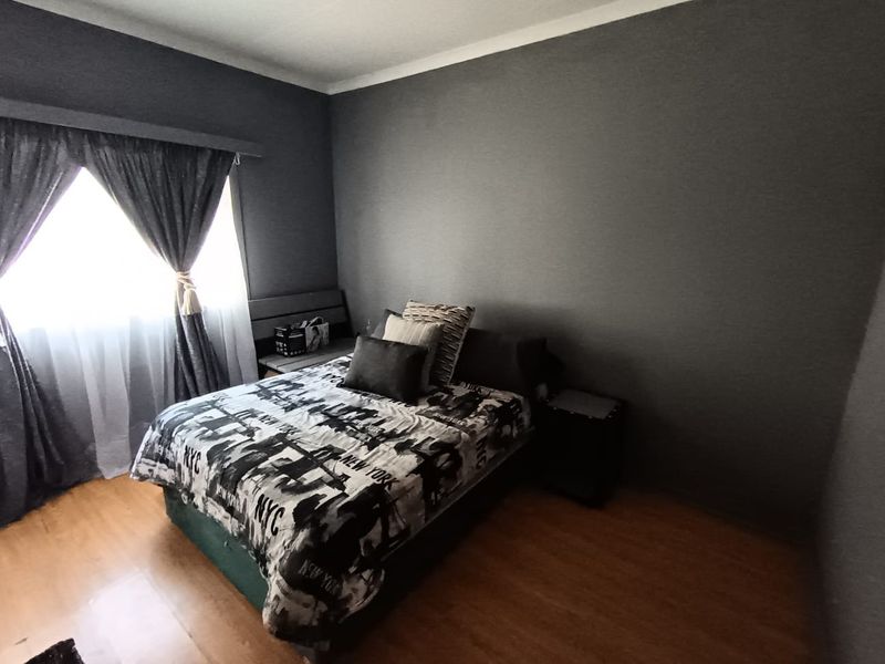 A bedroom featuring dark grey painted walls and laminate flooring, providing a neutral base for personalization.