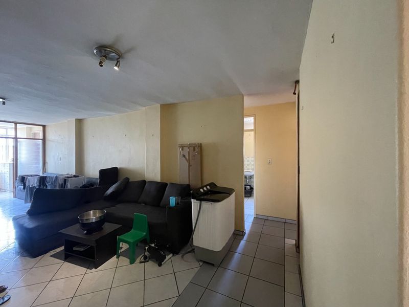 A living area featuring tiled flooring and neutral wall finishes, providing a functional space with direct access to adjacent rooms.