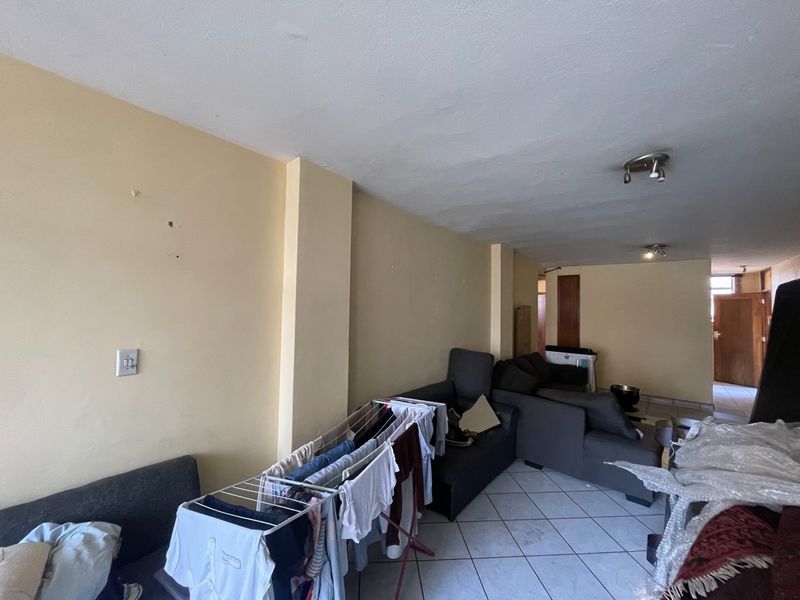 A living area featuring tiled flooring and neutral wall finishes, offering a blank canvas for potential renovation and interior design updates.