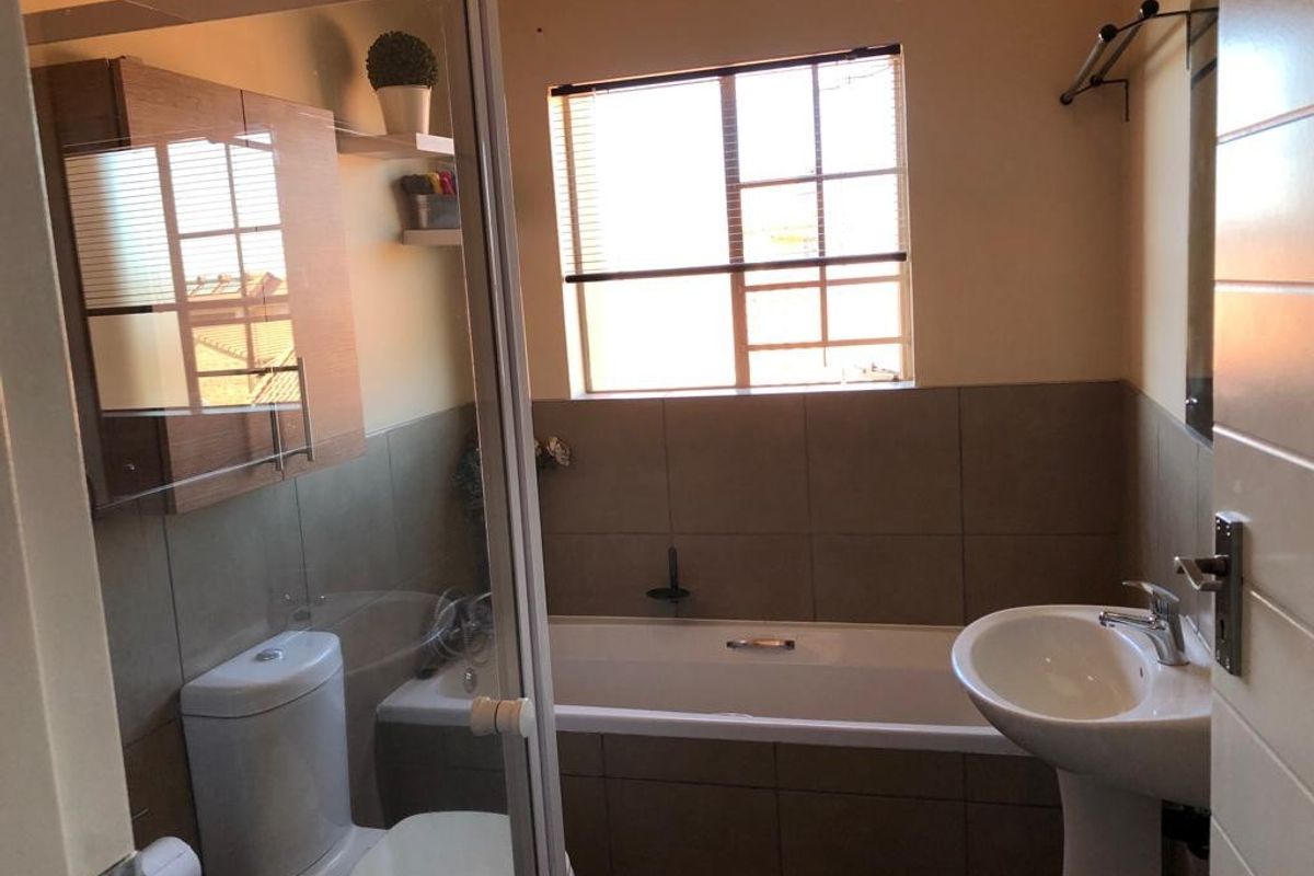 A functional bathroom featuring a pedestal basin, a built-in bathtub with tiled surround, a toilet, and a wall-mounted vanity cabinet.