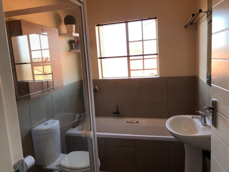 A functional bathroom featuring a pedestal basin, a built-in bathtub with tiled surround, a toilet, and a wall-mounted vanity cabinet.