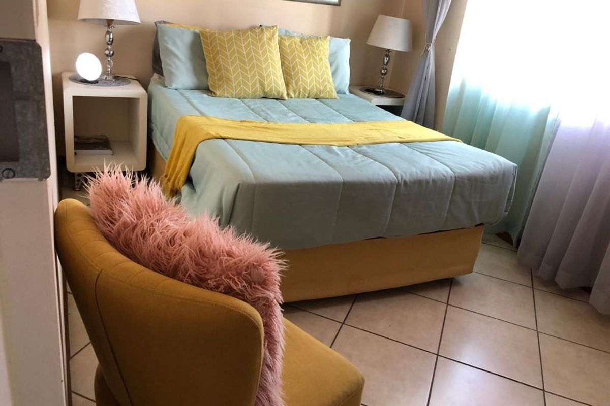 A cozy bedroom featuring tiled flooring and natural light from the window.