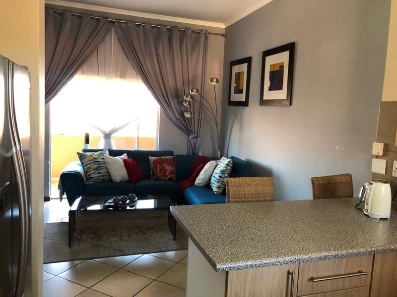 Open-plan living area featuring a functional kitchen with granite countertops and a seamless transition to the lounge, leading out to a balcony.