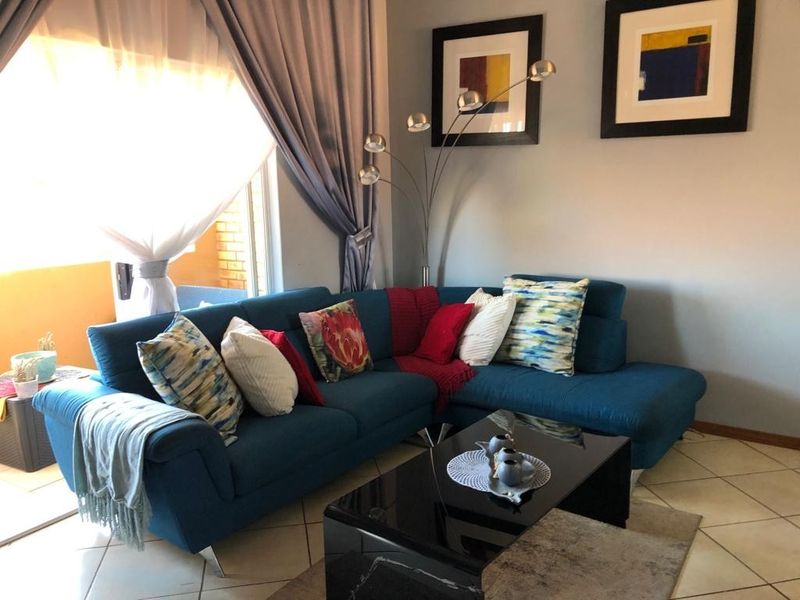 A comfortable living room featuring tiled flooring and a large sliding glass door that provides access to an outdoor area.