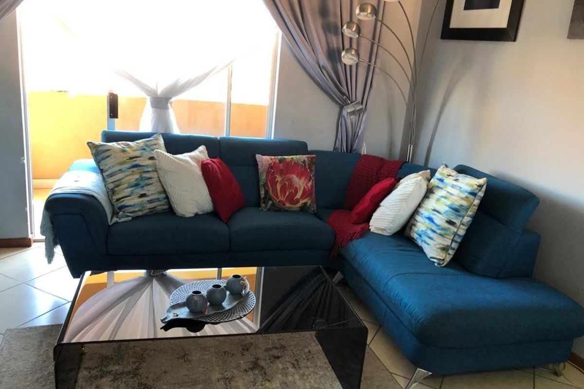 A comfortable living room area featuring tiled flooring and a large sliding glass door that provides access to an outdoor space.