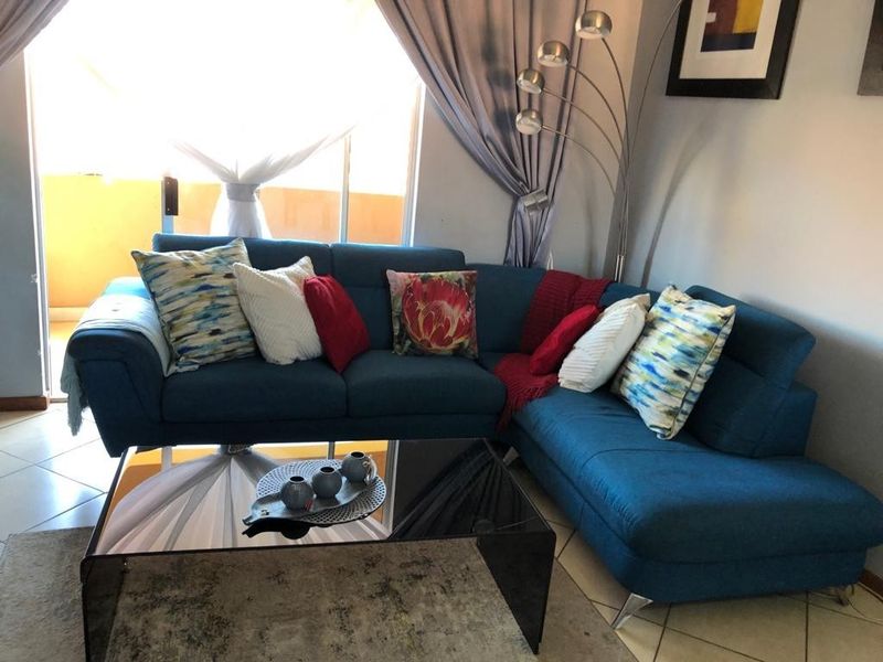 A comfortable living room area featuring tiled flooring and a large sliding glass door that provides access to an outdoor space.