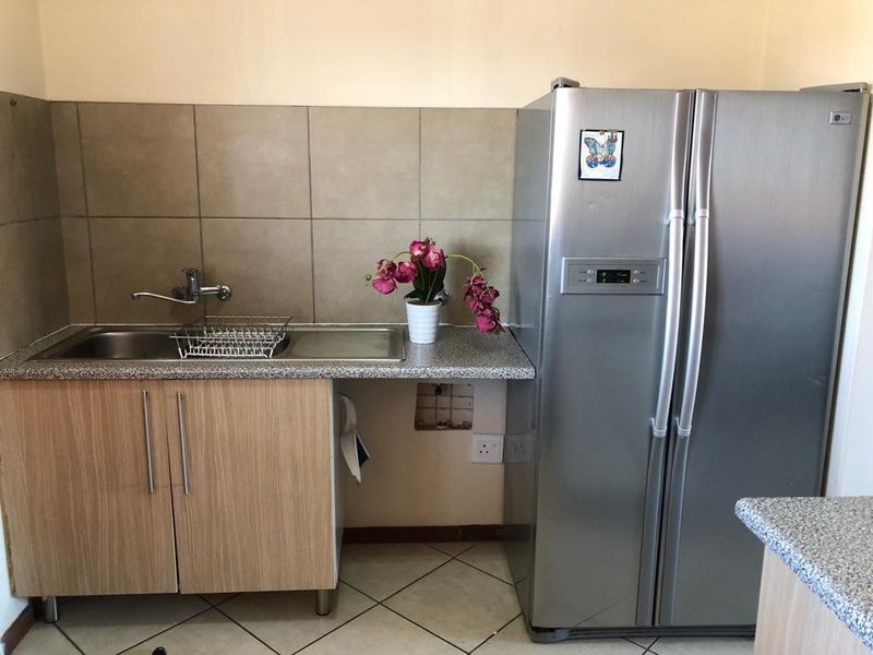 A compact kitchen area featuring laminate cabinetry, a stainless steel sink, and tiled splashbacks, requiring minor repairs to cabinetry and wall finishes.