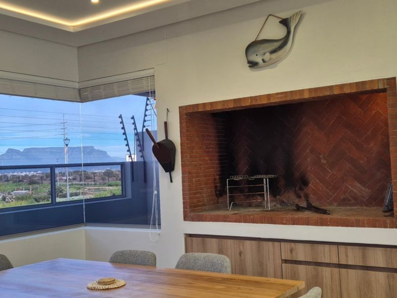 Living area featuring a built-in brick fireplace, recessed ceiling lighting, and large corner windows offering scenic mountain views.