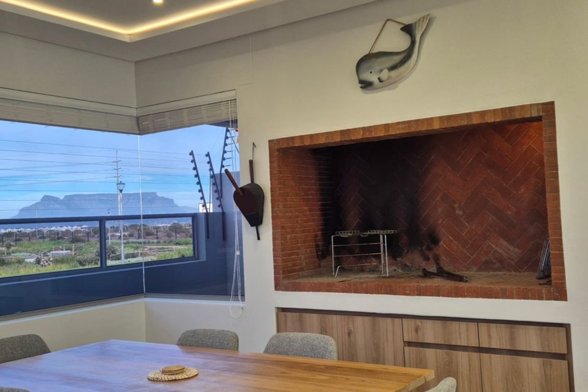 Living area featuring a built-in brick fireplace, recessed ceiling lighting, and large corner windows offering scenic mountain views.