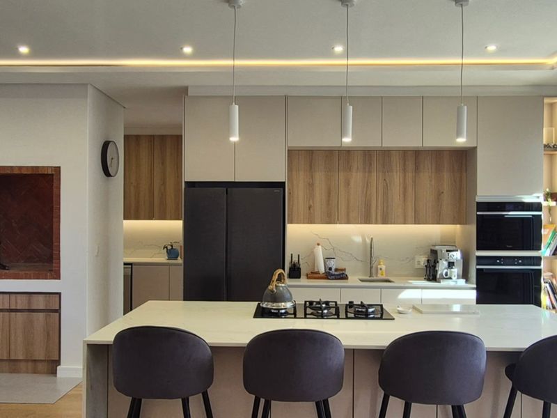 Modern open-plan kitchen featuring a central island with gas hob, integrated appliances, sleek cabinetry, and a built-in indoor braai area.