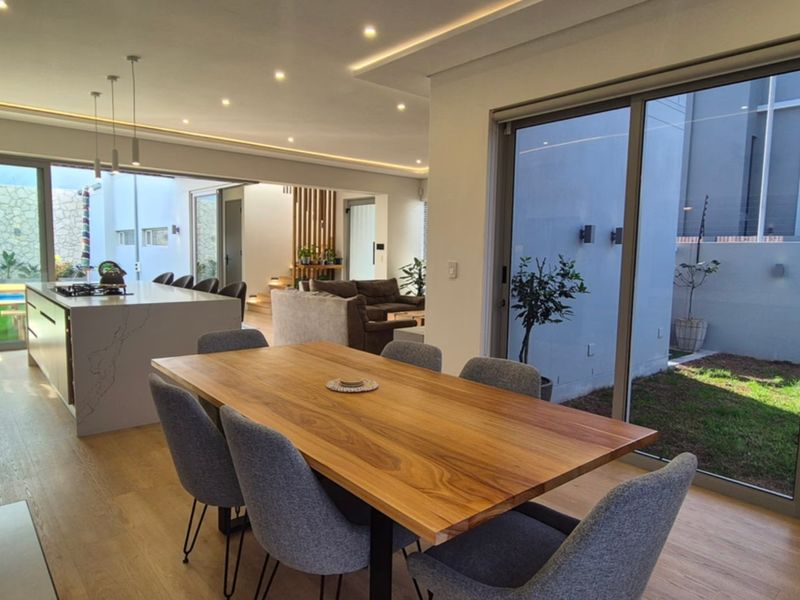 Modern open-plan living and dining area featuring high-end finishes, recessed lighting, and large sliding glass doors that provide seamless indoor-outdoor flow.