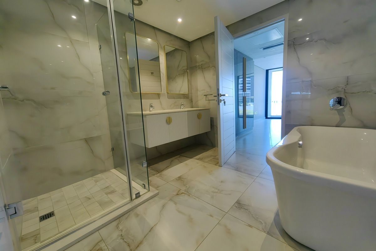 Modern luxury bathroom featuring a walk-in shower, freestanding bathtub, and double vanity with marble-look tiling throughout.