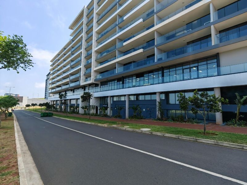 A modern multi-story apartment building featuring extensive glass balconies and a clean, contemporary architectural facade.