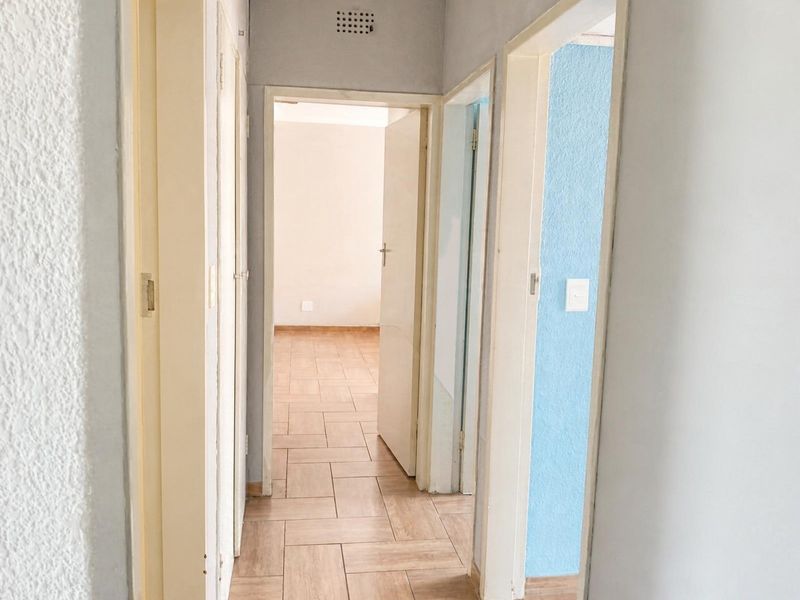 A functional hallway featuring tiled flooring and built-in storage cupboards, providing access to adjacent rooms within the townhouse.