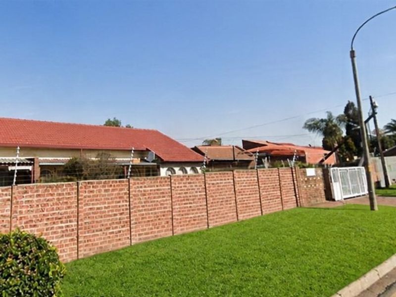 Street view of the townhouse property featuring a brick boundary wall with electric fencing and a tiled roof.