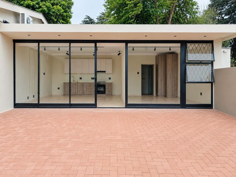 Modern open-plan living and kitchen area featuring large sliding glass doors opening onto a paved patio, offering a seamless indoor-outdoor flow.