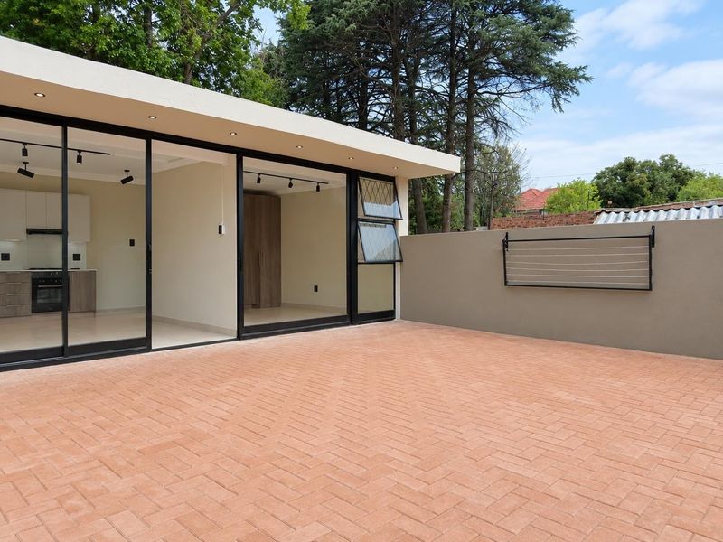 A spacious, modern paved patio area featuring large sliding glass doors that provide seamless access to the interior living space.