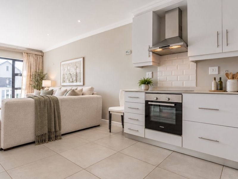 Modern open-plan living area featuring a sleek kitchen with built-in oven, extractor fan, subway tile backsplash, and direct access to a balcony.
