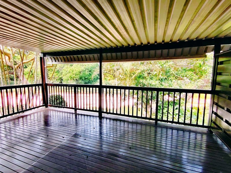 A spacious covered balcony featuring timber decking and a secure timber balustrade, offering a peaceful outlook over the surrounding greenery.