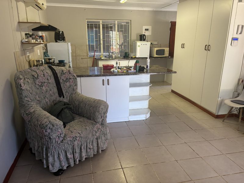 Open plan kitchen and living area featuring tiled flooring, built-in cabinetry, and a central island, offering a functional layout with potential for modernization.