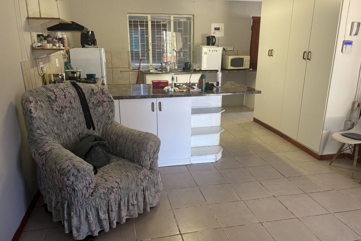 Open plan kitchen and living area featuring tiled flooring, built-in cabinetry, and a central island, offering a functional layout with potential for modernization.