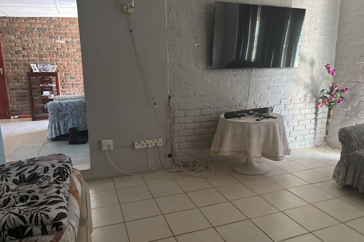 Living area featuring exposed brick walls and tiled flooring, requiring minor electrical maintenance and cosmetic updates to improve the overall finish.