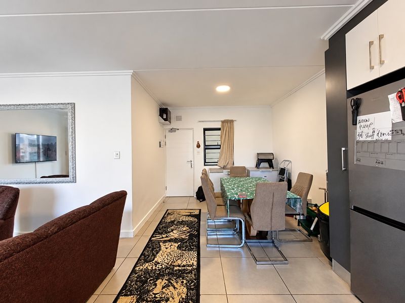 Open plan living and dining area featuring tiled flooring, neutral walls, and built-in kitchen cabinetry, providing a functional and versatile living space.