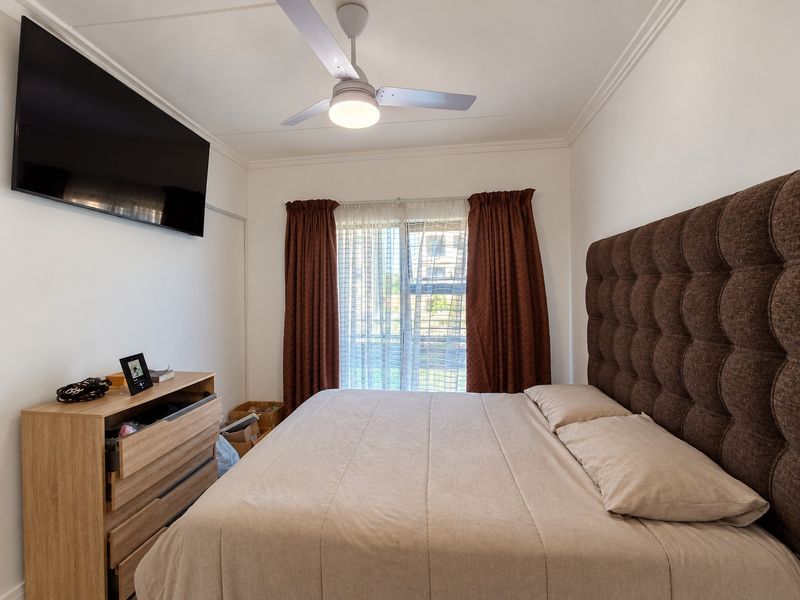 A well-maintained bedroom featuring a ceiling fan, crown molding, and a sliding glass door that provides natural light.