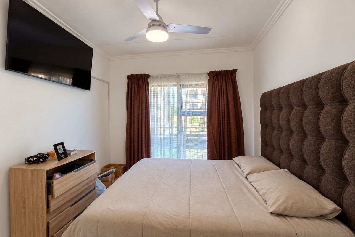 A well-maintained bedroom featuring a ceiling fan, crown molding, and a sliding glass door that provides natural light.