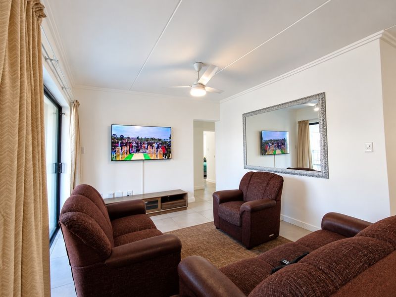 A well-maintained living room featuring tiled flooring, a ceiling fan, and a sliding glass door providing natural light.