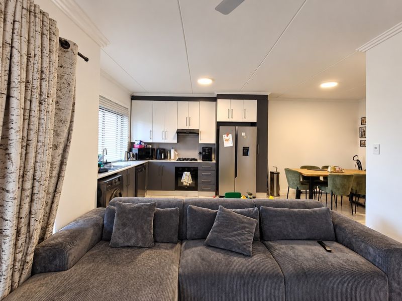 Open-plan living and kitchen area featuring modern two-tone cabinetry, built-in appliances, and a functional layout connecting the kitchen to the dining space.