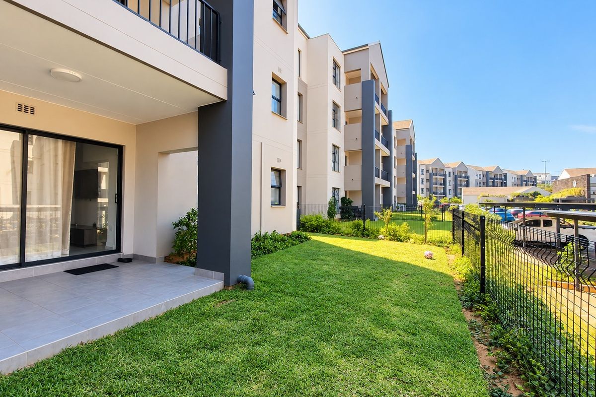 Ground floor apartment featuring a private tiled patio and a well-maintained garden area, enclosed by secure metal fencing.