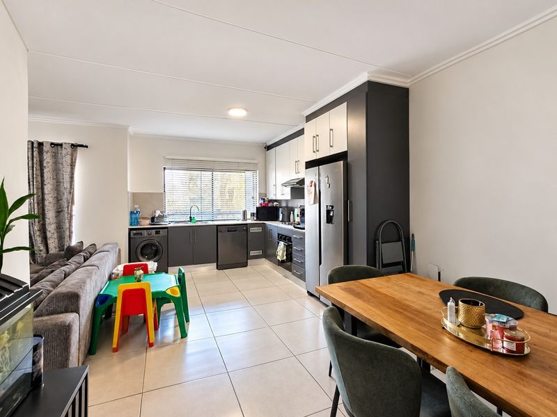 Open-plan living and kitchen area featuring modern two-tone cabinetry, tiled flooring, and a functional layout suitable for family living.