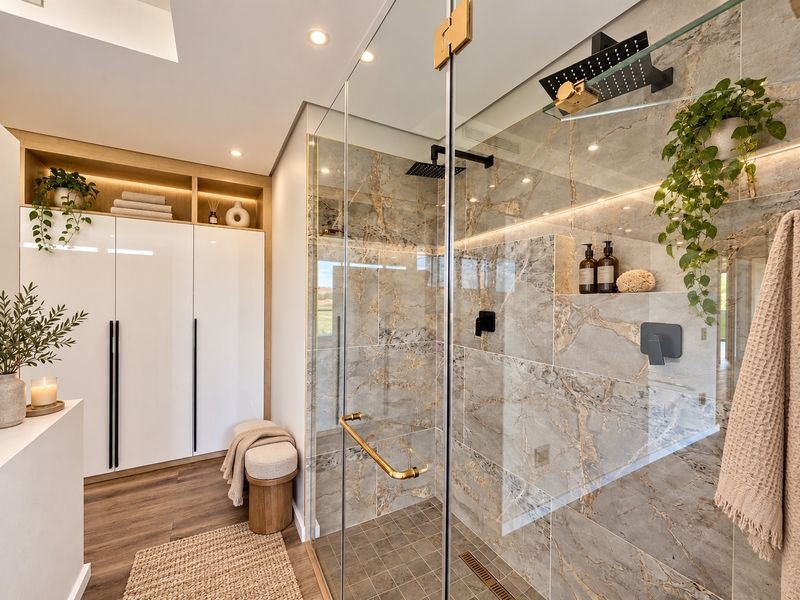 Modern bathroom featuring a spacious walk-in shower with marble-look tiling, integrated LED lighting, built-in shower niche, and sleek white cabinetry with open shelving.