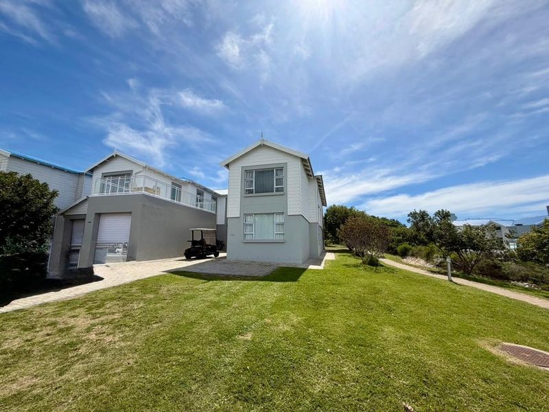 A well-maintained two-story residential property featuring a paved driveway, attached garage, and a balcony, set within a landscaped garden area.