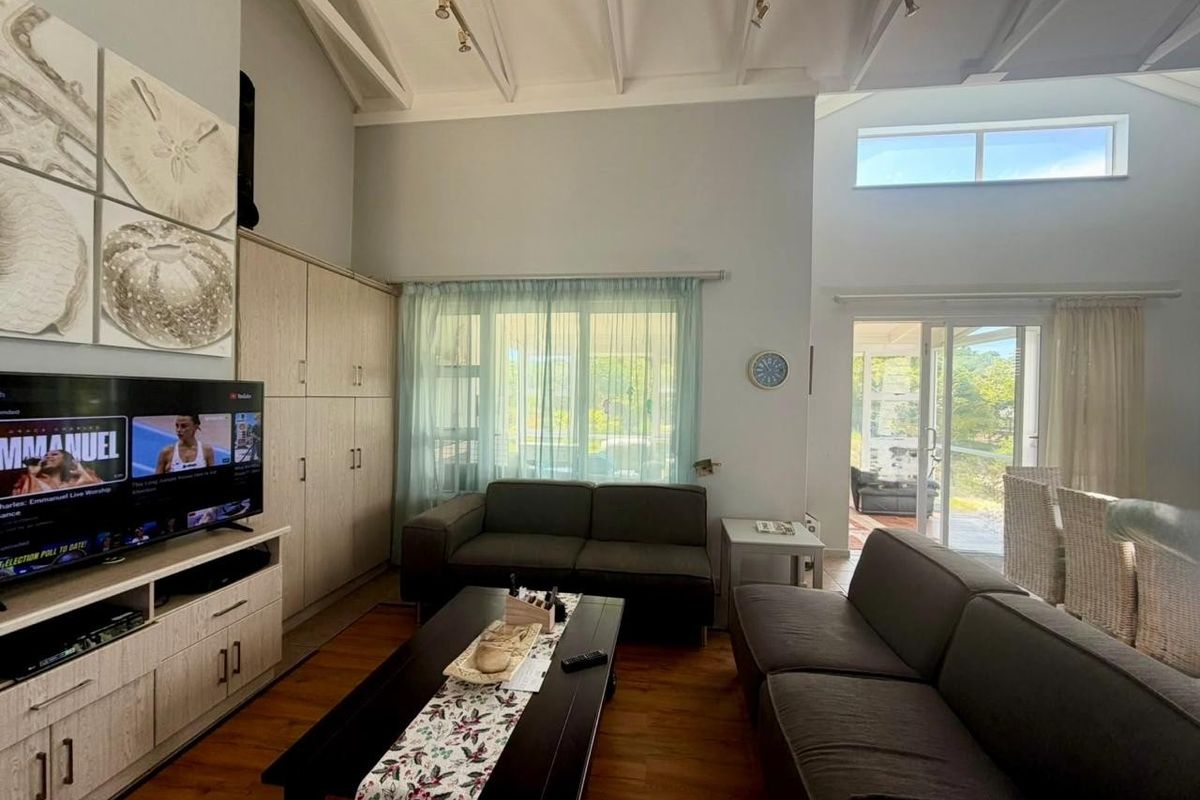Spacious living room featuring vaulted ceilings with exposed rafters, built-in cabinetry, and large sliding glass doors that provide ample natural light and garden access.