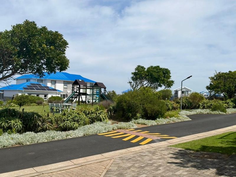 A view of the property exterior featuring a well-maintained garden, paved driveway, and solar panels installed on the roof.