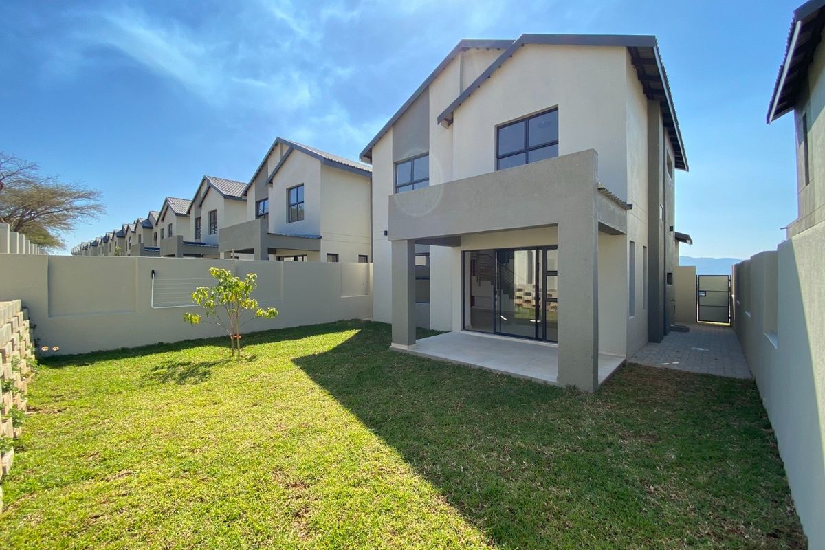 Rear view of a modern two-story house featuring a covered patio, sliding glass doors, and a private garden with a boundary wall.