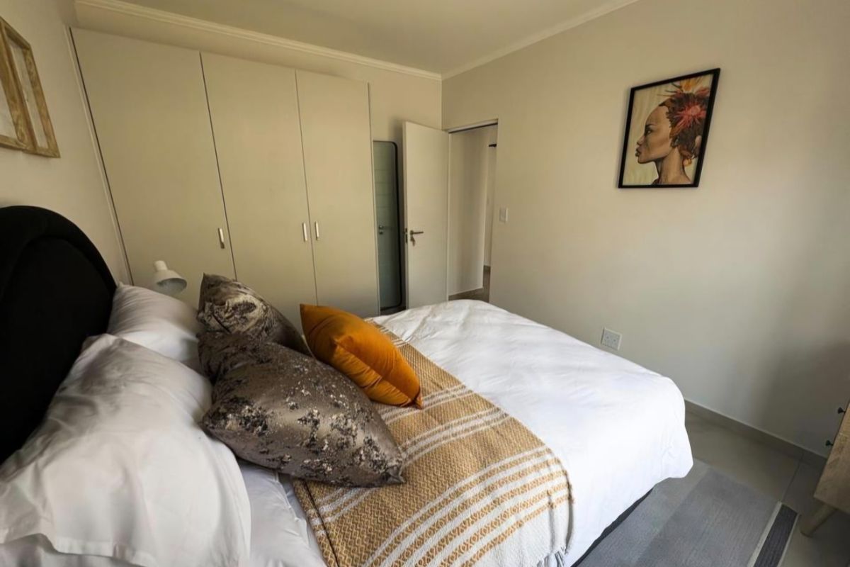 A well-maintained bedroom featuring built-in cupboards, neutral wall finishes, and tiled flooring, offering a clean and functional living space.