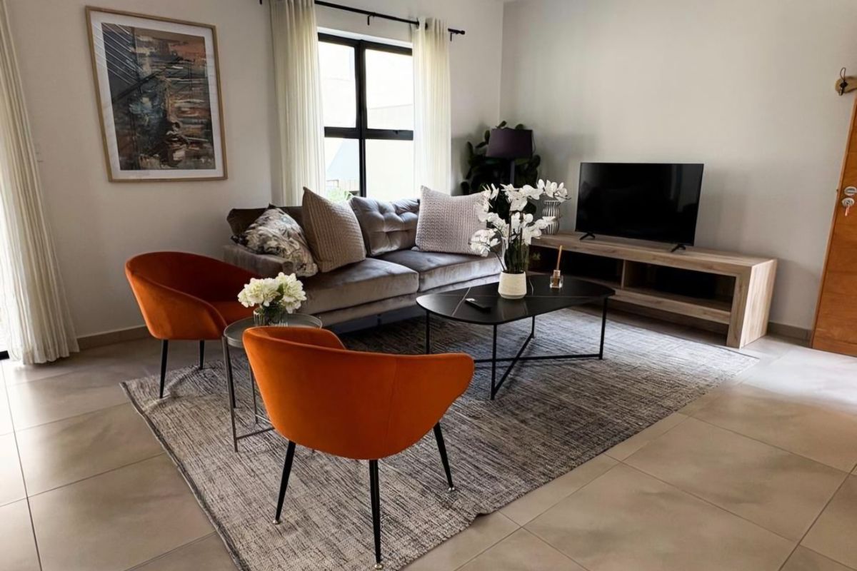 A well-maintained living room featuring neutral tiled flooring and a large window that provides natural light to the space.